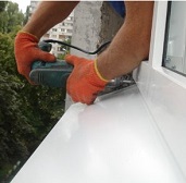 Мастер устанавливают металлический оконный отлив